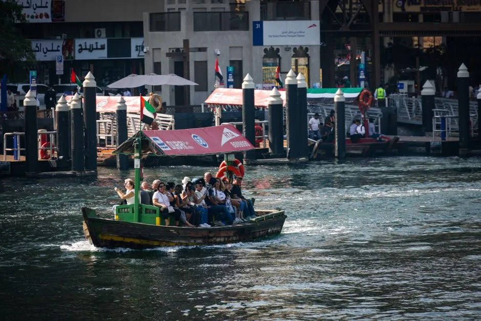 A busy abra station on Dubai Creek with wooden water taxis moored at the quay on the Deira side
