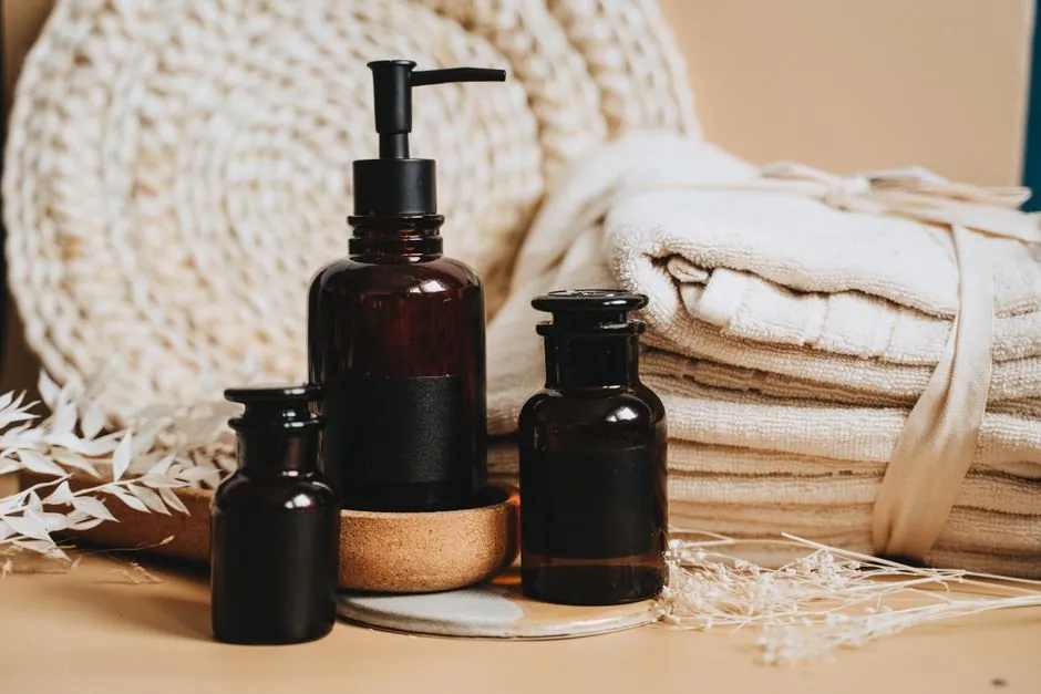 Massage oil bottles standing beside a stack of folded fresh towels